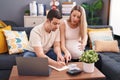 Man and woman couple expecting baby writing on notebook accounting at home