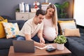 Man and woman couple expecting baby writing on notebook accounting at home