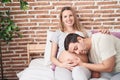 Man and woman couple listening baby sound sitting on bed at bedroom