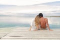 Man and woman couple sitting on a Jetty under a blue cloudy sky Royalty Free Stock Photo