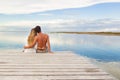 Man and woman couple sitting on a Jetty under a blue cloudy sky Royalty Free Stock Photo