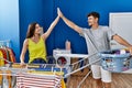 Man and woman couple smiling confident high five at laundry room