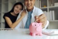 Man and woman couple smiling confident insert coin on piggy bank at home Royalty Free Stock Photo