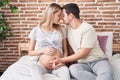 Man and woman couple touching belly sitting on bed at bedroom Royalty Free Stock Photo