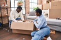 Man and woman couple unboxing cardboard box sitting on floor at new home Royalty Free Stock Photo