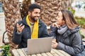 Man and woman couple using laptop drinking coffee at coffee shop terrace Royalty Free Stock Photo