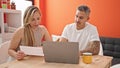 Man and woman couple using laptop reading document at dinning room Royalty Free Stock Photo