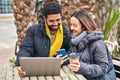 Man and woman couple using laptop and smartphone drinking coffee at coffee shop terrace Royalty Free Stock Photo