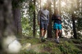 Man and woman couple walking in forest woods with sun flare light. Group of friends people summer adventure journey in