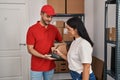 Man and woman deliveryman and worker holding package signing on dataphone at storehouse
