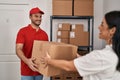 Man and woman deliveryman and worker holding package at storehouse