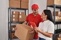 Man and woman deliveryman and worker holding package and using touchpad at storehouse