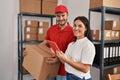 Man and woman deliveryman and worker holding package and using touchpad at storehouse