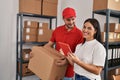 Man and woman deliveryman and worker holding package and using touchpad at storehouse