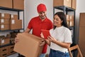 Man and woman deliveryman and worker holding package and using touchpad at storehouse