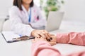 Man and woman doctor and patient having medical consultation with hands together at clinic Royalty Free Stock Photo