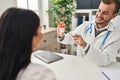 Man and woman doctor and patient having medical consultation holding urine analysis bottle at clinic Royalty Free Stock Photo