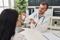 Man and woman doctor and patient having medical consultation holding urine analysis bottle at clinic Royalty Free Stock Photo