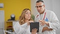 Man and woman doctors using touchpad speaking at the clinic