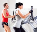 Man and woman with elliptical cross trainer at gym