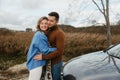 A man and a woman embrace happily in front of a car, smiling under the sky Royalty Free Stock Photo