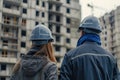 A man and a woman engineers wearing hard hats, standing confidently against a backdrop of a construction site