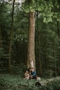 man and woman, enjoying walk in the forest, sitting under the big tree, hugging and kissing Royalty Free Stock Photo