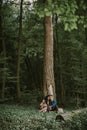 man and woman, enjoying walk in the forest, sitting under the big tree, hugging and kissing Royalty Free Stock Photo