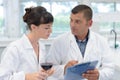 Man and woman experts in white coats checking wine quality