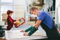 Man and woman in face masks working on glass pane in glazier workshop Royalty Free Stock Photo