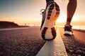 A close-up man or woman athlete feet jogging on road for workout in wellness concept at sunrise. Royalty Free Stock Photo