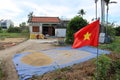 A man and a woman fill sacks of rice next to their house with the Vietnamese flag during the first rice harvest of 2021 in Hoi An Royalty Free Stock Photo