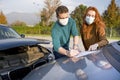 Man and woman filling an insurance car report after car crash wearing face mask for corona Royalty Free Stock Photo