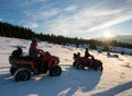 Man and woman on four-wheelers ATV bikes on snow, enjoying sunset in the the mountains in winter Royalty Free Stock Photo