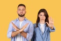 Man and woman gesturing stop, showing denial or refusal on yellow background Royalty Free Stock Photo