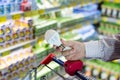 Man or woman hand holding energy efficient diodes light bulb lamp with trolley on the supermarket, DIY department store