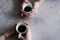 Man and woman hands holding coffee cups on grey background.