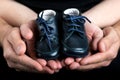 Man and Woman Hands Holding a Pair of Baby Shoes Royalty Free Stock Photo