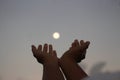 Man and woman hands reaching out to the full moon in the sky on blue sky background. Royalty Free Stock Photo