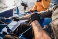 Man and woman hands ulling winch rope on sailing boat