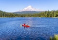 Man and woman in hats ride kayak on the picturesque Trillium Lake overlooking Mount Hood Royalty Free Stock Photo