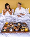 man and woman having breakfast in bed, couple having breakfast with coffee bread and fruit in bedroom Royalty Free Stock Photo