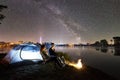 Man and woman having a rest on shore under night sky