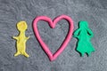 Man and woman with Heart made of play dough in front of grey background Royalty Free Stock Photo
