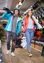 man and woman in helmets choosing sports equipment