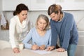Married couple helps elderly mother write her testament in kitchen Royalty Free Stock Photo