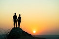 Man and woman hikers standing on a big stone at sunset in mountains. Couple together on a high rock in evening nature. Tourism, Royalty Free Stock Photo