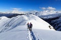 Man and woman hiking on snowshoes and mountain snow panorama with blue sky in Stubai Alps