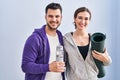 Man and woman hoilding yoga mat and bottle of water standing at sport center