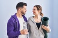 Man and woman hoilding yoga mat and bottle of water standing at sport center